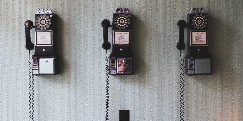 Three old fashion public phones hanging on a wall